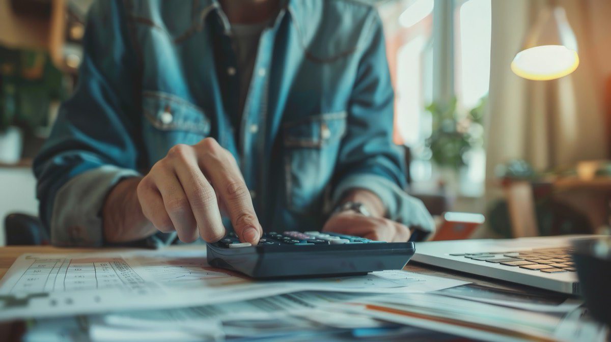 Pessoa usando calculadora financeira para planejar economia e investimentos