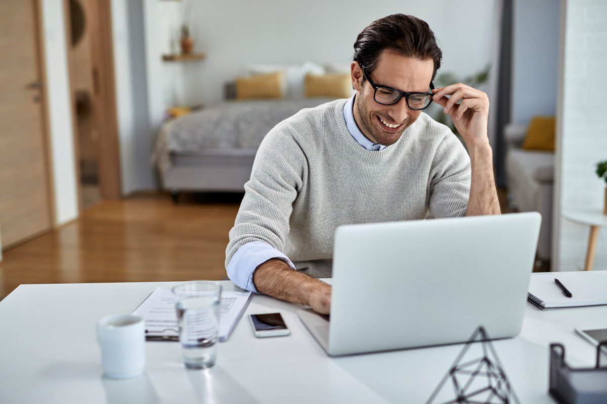 Freelancer sorridente trabalhando no computador em casa